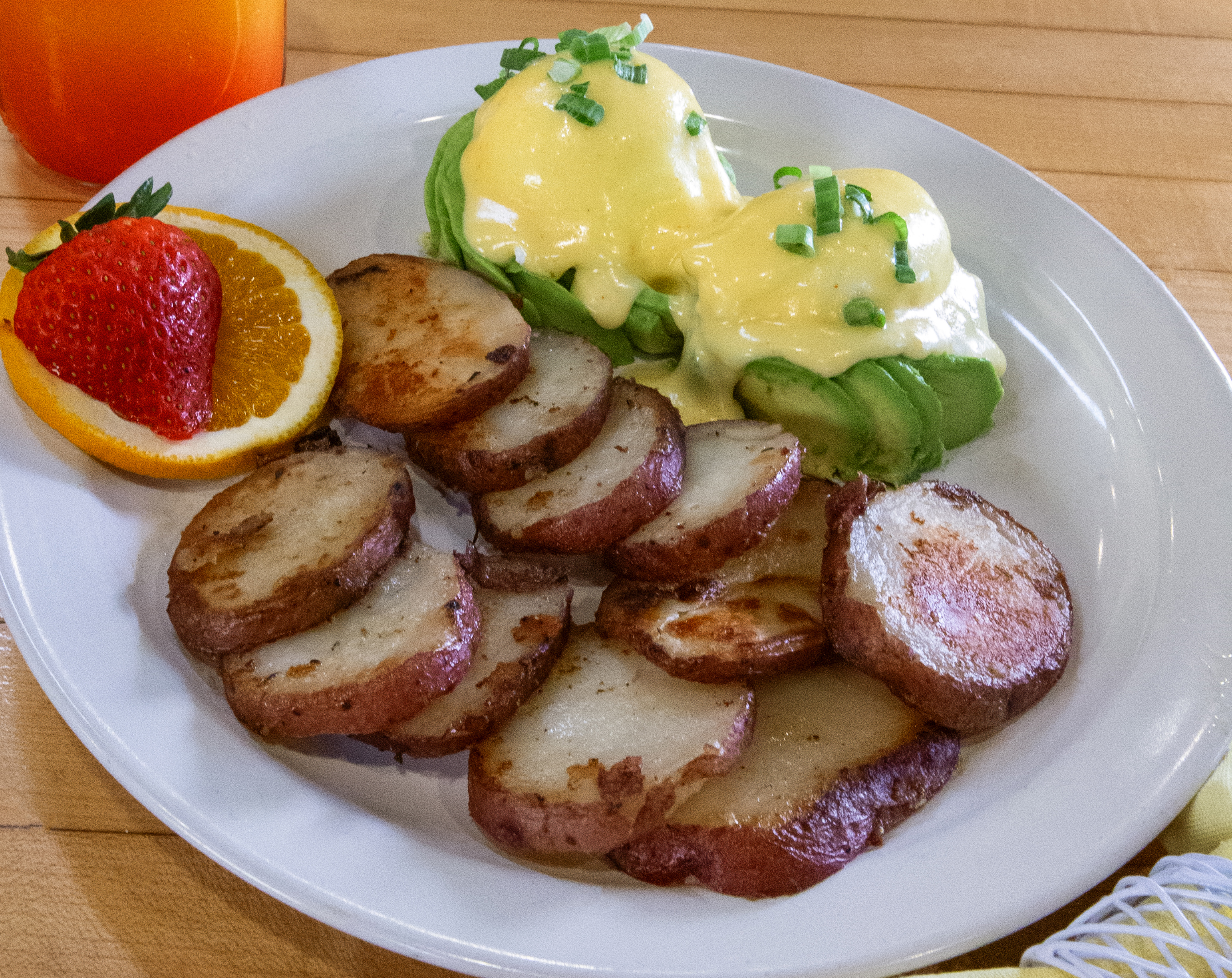 Gluten-free avocado Benedict with breakfast potatoes and fresh fruit